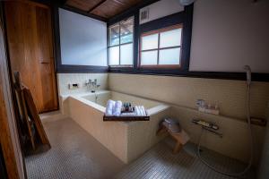 a bathroom with a tub and a shower and a toilet at Japan's oldest remaining company housing in Ikuno