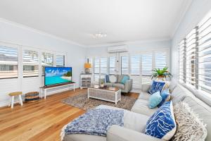 a living room with a white couch and a tv at Waterfront at Sunset Boulevard 26 Sunset Boulevard in Soldiers Point