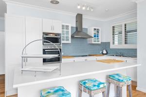 a kitchen with white cabinets and blue tiles at Waterfront at Sunset Boulevard 26 Sunset Boulevard in Soldiers Point