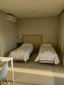 a bedroom with two beds and a table and a desk at TORRE GUAYASAMIN in Corrientes