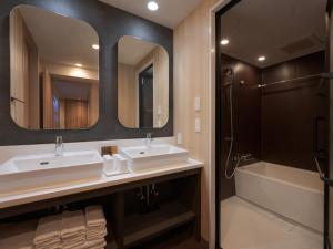 a bathroom with two sinks and a tub and a mirror at MIMARU OSAKA SHINSAIBASHI EAST in Osaka
