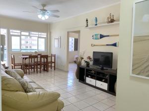un soggiorno con un divano e una televisione di APARTAMENTO NA PRAIA GRANDE A 200 MÉTROS DA PRAIA, CONFORTÁVEL ESPAÇOSO WIFI 350 Mega TV Claro, ÓTIMA LOCALIZAÇÃO a Praia Grande