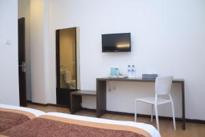a room with a desk with a chair and a television at Sunwood Hotel Arianz Mataram in Mataram