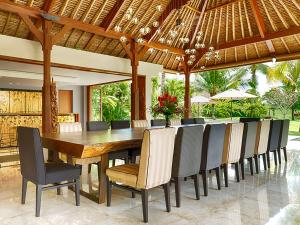 an outdoor dining room with a wooden table and chairs at Kaba Kaba Estate in Tabanan