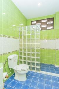 baño con aseo y pared de azulejos verdes en Evergreen boutique Hua Hin, en Hua Hin