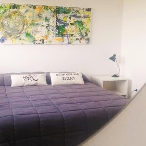 a bedroom with a purple bed with a painting on the wall at HOMU DEP - Puerto deseado in Puerto Deseado