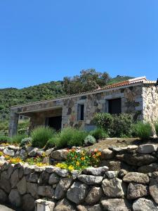 ein Steinhaus mit einer Steinmauer und Blumen in der Unterkunft Charmante maison de village *** in Santa-Maria-Figaniella
