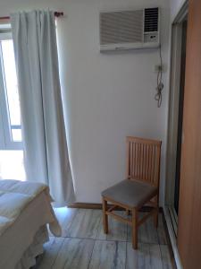 una camera da letto con una sedia e una finestra con condizionatore d'aria di Arcángeles a Rosario