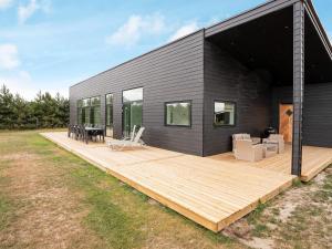 una casa nera con una terrazza in legno in un cortile di Holiday home Væggerløse CCXIII a Bøtø By