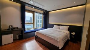 Un dormitorio con una cama grande y una ventana en Gold Stone Hotel, en Busan