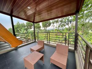 een balkon van een huis met 2 stoelen en bomen bij Villa La Vimala in Gadok 1