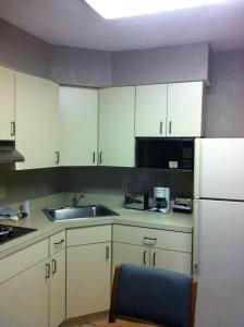 a kitchen with white cabinets and a sink and a refrigerator at East Street Inn & Suites in Tipton