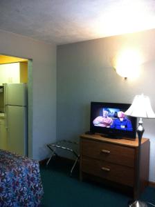 a hotel room with a television on a dresser with a lamp at East Street Inn & Suites in Tipton