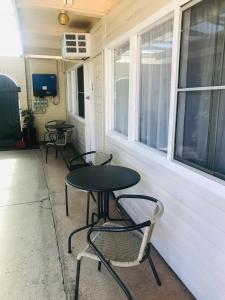 een patio met 2 tafels, stoelen en ramen bij Kaputar Motel in Narrabri