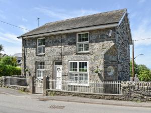 an old stone house with a fence in front of it at Bryn Y Felin in Dyffryn