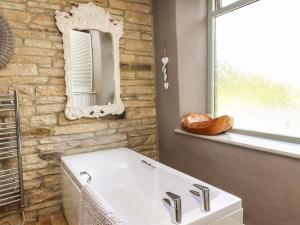 uma casa de banho com um lavatório branco e um espelho. em Woodman Cottage em Skipton