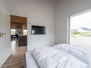 1 dormitorio blanco con 1 cama y TV en la pared en Holiday home Henne CXXVI en Henne Strand