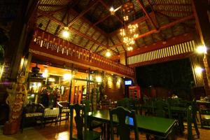 a restaurant with a green table and chairs at night at Irawadee Resort in Mae Sot