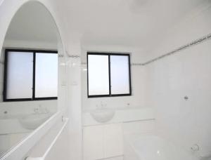 a white bathroom with two sinks and two windows at Hi Surf Unit 2, 92 Head Street, Forster in Forster