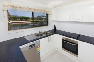 eine Küche mit weißen Schränken, einem Waschbecken und einem Fenster in der Unterkunft LAKE HOUSE ON ELOUERA in Forster