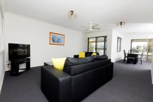 a living room with a black couch and a tv at LAKE HOUSE ON ELOUERA in Forster