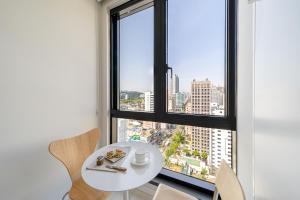 una mesa y sillas blancas en una habitación con ventana en Urbanstay Seomyeon en Busan