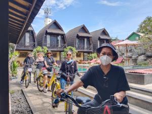 a group of people riding bikes in front of a house at Bale Sasak Bungalow in Gili Trawangan