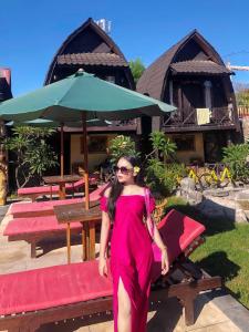 a woman in a red dress standing in front of a table at Bale Sasak Bungalow in Gili Trawangan