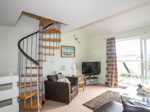 a living room with a spiral staircase and a couch at Machlud Ynys in Y Felinheli