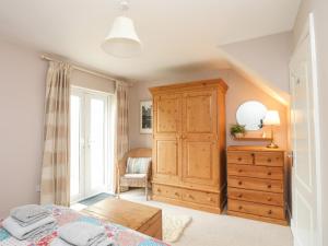 a bedroom with a bed and a dresser and a window at Machlud Ynys in Y Felinheli