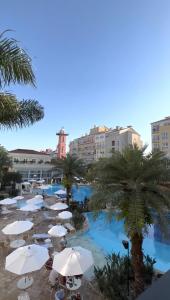 a pool with white umbrellas and palm trees and buildings at Il Campanario in Florianópolis