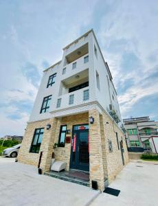 un grand bâtiment avec une porte bleue dans un parking dans l'établissement 金門禧樂民宿, à Shan-ch'ien