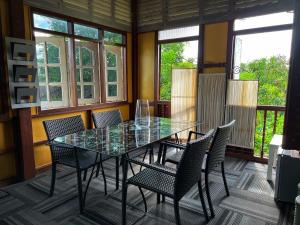 une table et des chaises en verre dans une pièce avec fenêtres dans l'établissement Kejora Homestay, à Kangar