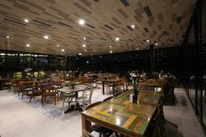 un restaurante con mesas y sillas y gente de fondo en Sunsetfalls Gardens and Resort, en Magelang