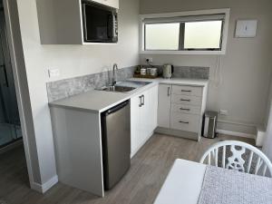 a small kitchen with a sink and a microwave at Raglan Retreat on Gilmour in Raglan +10 photos