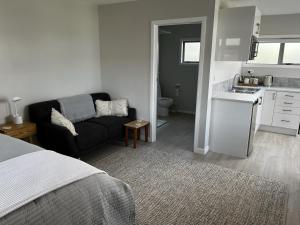 a living room with a couch and a kitchen at Raglan Retreat on Gilmour in Raglan