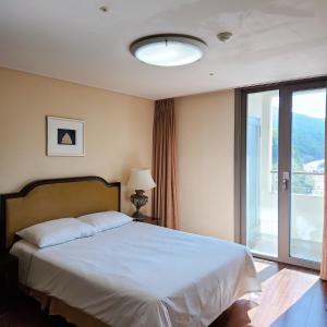 a bedroom with a bed and a large window at Jeongseon Mayhills Resort in Jeongseon