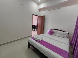 1 dormitorio con 1 cama grande y cortinas moradas en Lishan Apartment, en Mysore