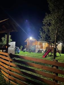 een hek in een tuin met 's nachts een speeltuin bij Wooden House Ripac in Bihać
