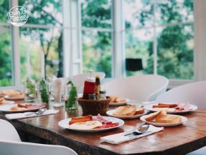 una mesa de madera con platos de comida. en สวนลุงวรRanongGlamping, en Ban Bang Hin