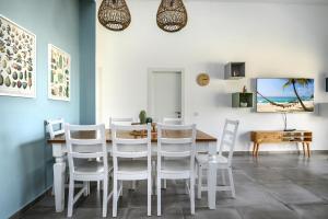 納哈里亞的住宿－סוויטת עמית- נופש משפחתי 5 דקות הליכה מהים，一间带桌子和白色椅子的用餐室