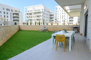 a patio with a table and chairs and grass at סוויטת עמית- נופש משפחתי 5 דקות הליכה מהים in Nahariyya