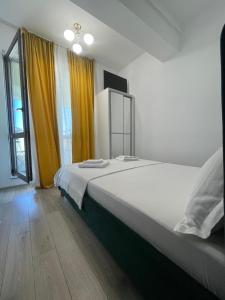 Schlafzimmer mit einem großen Bett und gelben Vorhängen in der Unterkunft Charming apartment near Palass Mall in Iaşi