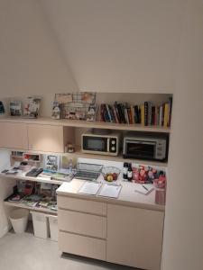 een keuken met een aanrecht met een magnetron en boeken bij B&B De Stuifduinen in Wetteren