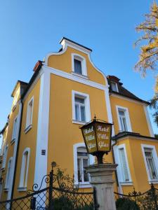 un bâtiment jaune et blanc avec un panneau devant lui dans l'établissement Hotel Villa Glas, à Erlangen