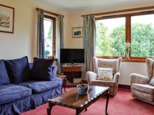 a living room with a couch and chairs and a tv at Coille Mhor in Clunie