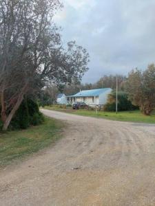 a dirt road leading to a house with a blue roof at White Cottage on Ninety Mile Beach in Seaspray