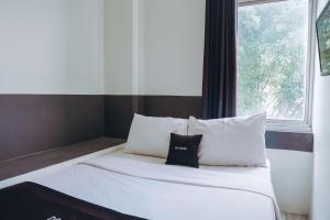 a bed with white sheets and pillows next to a window at DS Colive Layur Kota Lama in Semarang