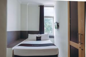 a small bed in a room with a window at DS Colive Layur Kota Lama in Semarang