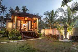 a house with a porch with a statue in the yard at VILLA JUAN - A Beach Front Villa in General Luna Siargao in General Luna